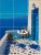 Mediterranean tile mural with blue-accented terrace, wine, table setting, and sea view