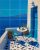 Mediterranean tile mural with blue-accented terrace, wine, table setting, and sea view